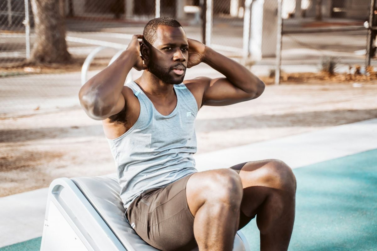 man in white tank top and gray shorts sitting on white car