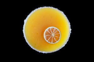 A glass of orange juice with a slice taken out of it