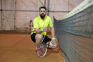 Man with beard holding tennis racket on court