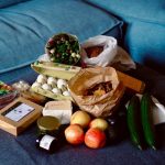 Groceries are arranged on a blue sofa.