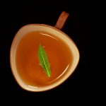 A cup of tea with a green leaf.