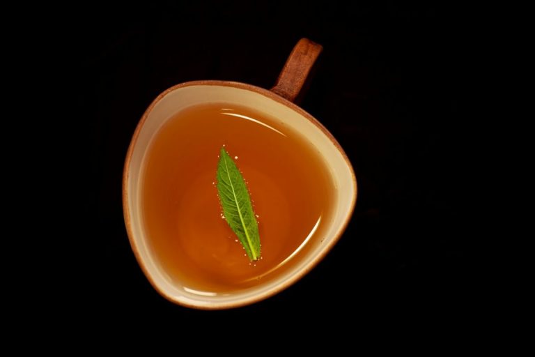 A cup of tea with a green leaf.