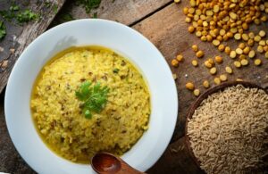 white ceramic bowl with yellow soup and moringa