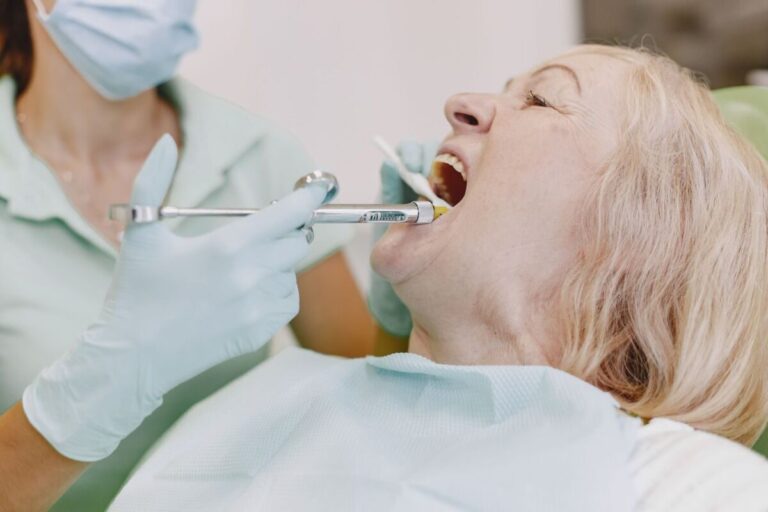 Senior woman undergoing dental examination with dentist using syringe and tools.