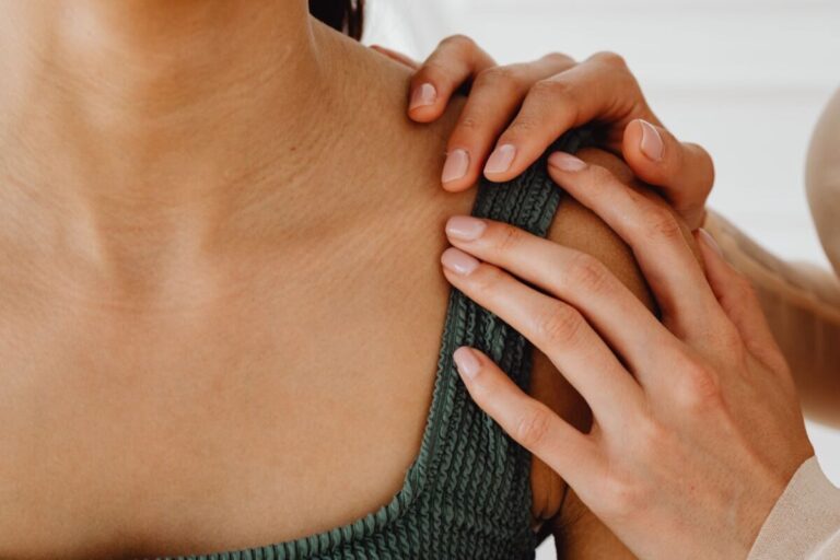 A close-up of hands gently resting on a shoulder, conveying care and comfort.