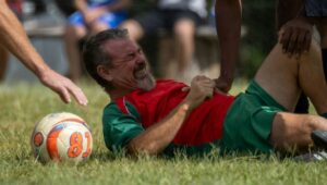 Man in soccer uniform grimacing on grass