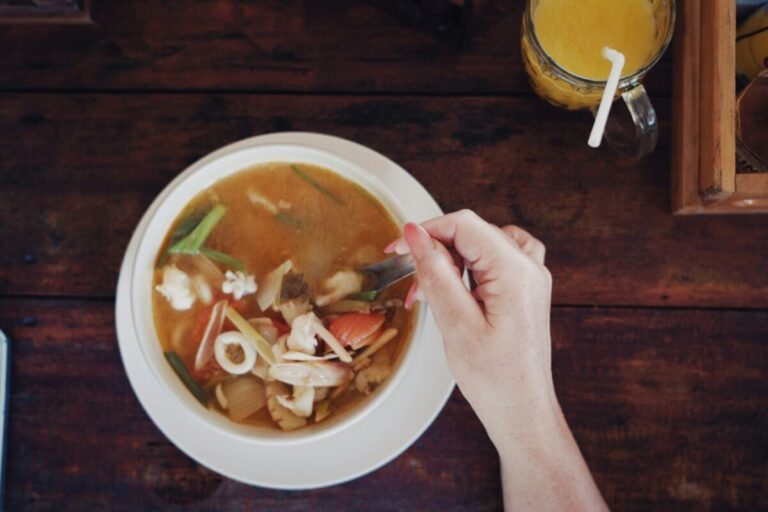 a person holding a spoon in a bowl of soup