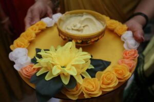 A yellow tray with a bowl of food and flowers